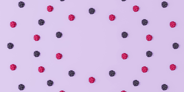 Pattern of ripe raspberries and blackberries laid out in a circle on a purple background with shadow and highlights  - 3D illustration