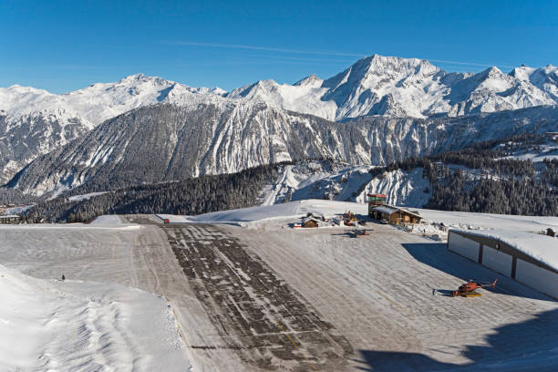 Altiport airport in a snow covered alpine mountain range Panoramic landscape view of small airport altiport runway on the side of a snow covered alpine mountain range in winter courchevel stock pictures, royalty-free photos & images