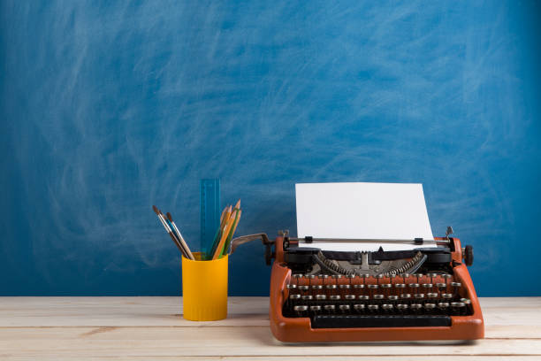 istock writer's workplace - red typewriter and stationery on blue blackboard background 1141955229