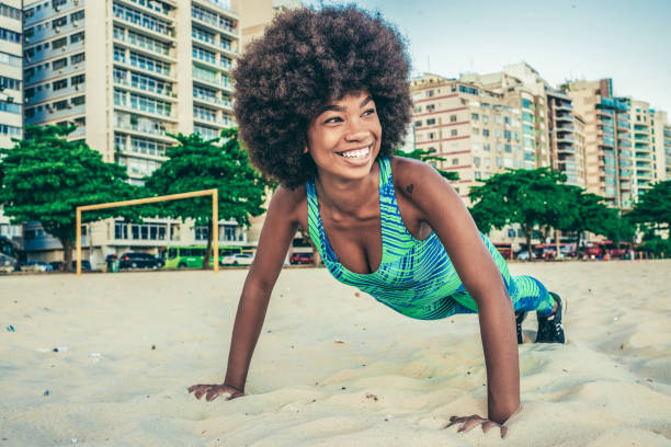 young woman doing push ups on the beach
