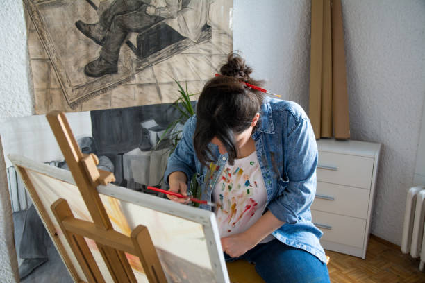 artiste femelle regardant sa chemise pleine de couleurs - tempera painting tube paint colors photos et images de collection