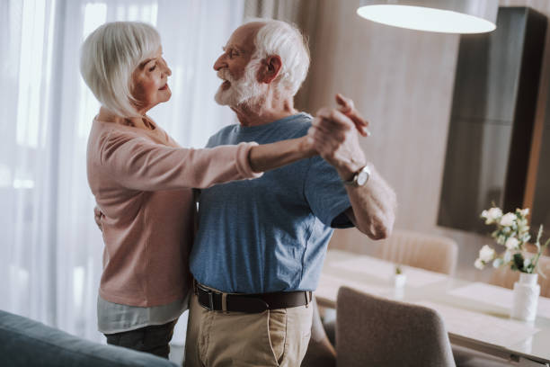 istock Joyful gray haired couple dancing in living room 1141960086