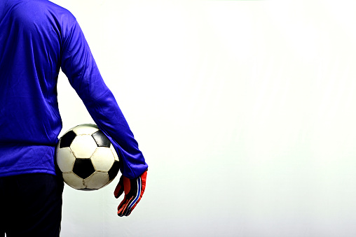 Back view of 8 years old boy wearing blue soccer uniform with number 17 and holding blue ball.