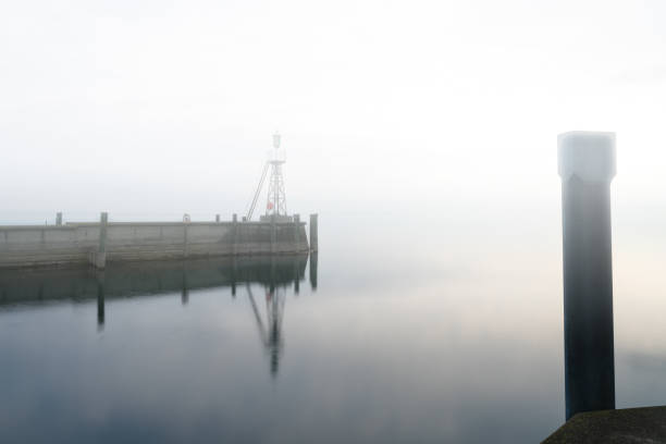 istock signal light and harbor wall on calm lake waters under an overcast sky negative space abstract 1141963828