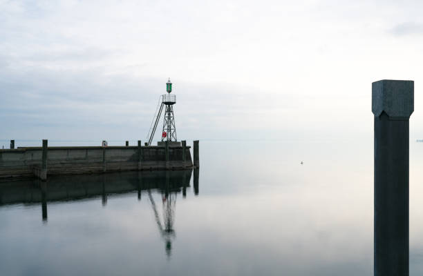 istock signal light and harbor wall on calm lake waters under an overcast sky negative space abstract 1141964014