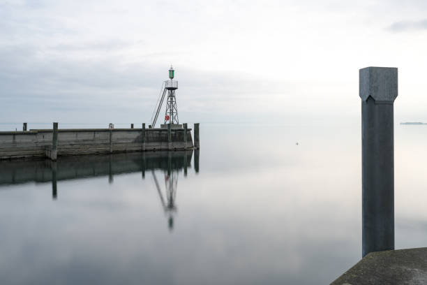 istock signal light and harbor wall on calm lake waters under an overcast sky negative space abstract 1141964032