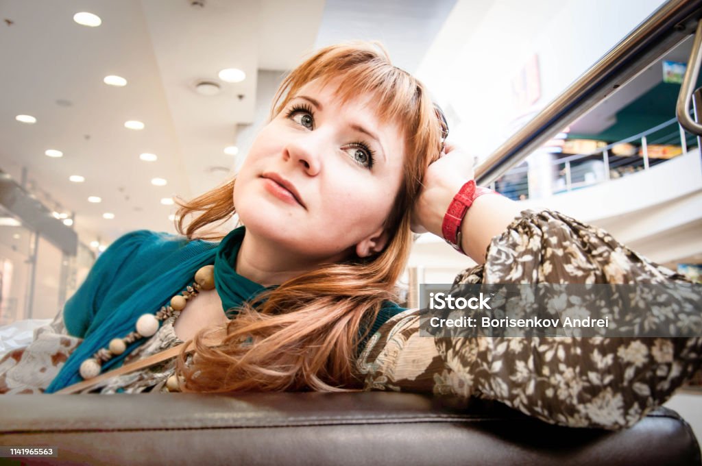 Girl resting on the couch in a large shopping center. Light-skinned girl with brown hair. Close-up. Adult Stock Photo