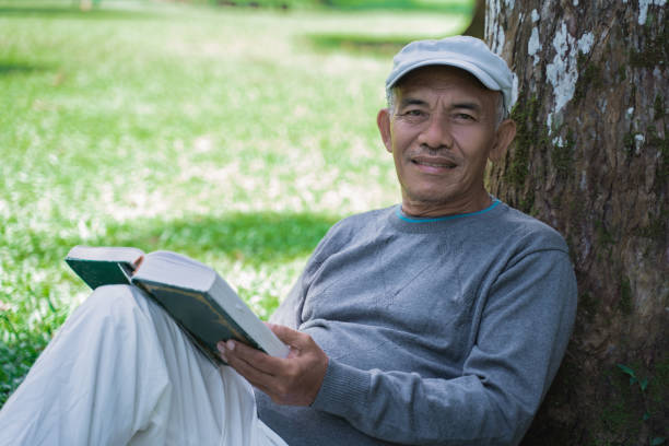 istock senior asian old man reading a book outdoor 1141965679