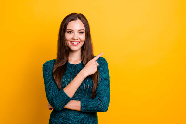 close up foto maravilhosa incrível ela ela senhora branco dentes longos cabelos lisos indicar dedo espaço vazio aconselhar comprar comprador desgaste verde malha pulôver jumper roupa isolado fundo amarelo - straight hair fashion model women long hair - fotografias e filmes do acervo