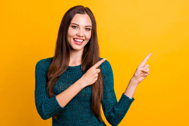 istock Close up photo beautiful her she lady white teeth indicate arm finger empty space advising buy buyer new clothes prices long straight hair wear green knitted pullover jumper isolated yellow background 1141969112