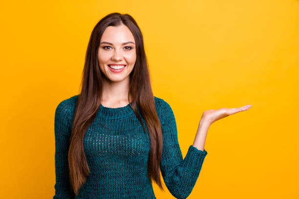 istock Close up photo beautiful her she lady indicate direct arm hand open palm empty space advising buy buyer pay payment customer prices wear green knitted pullover jumper isolated yellow background 1141969526