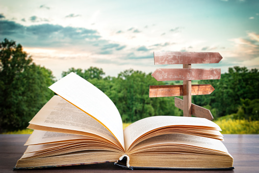 open book on a wooden surface and a wooden pointer in the background