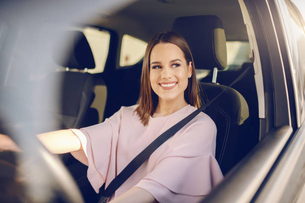 splendida bruna caucasica con un grande sorriso dento alla guida dell'auto. mani sul volante. - woman driver foto e immagini stock