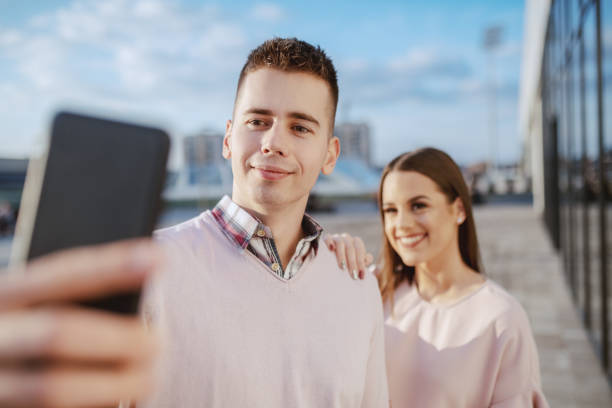 istock Cute cheerful Caucasian couple standing outdoors and taking selfie. 1141974902