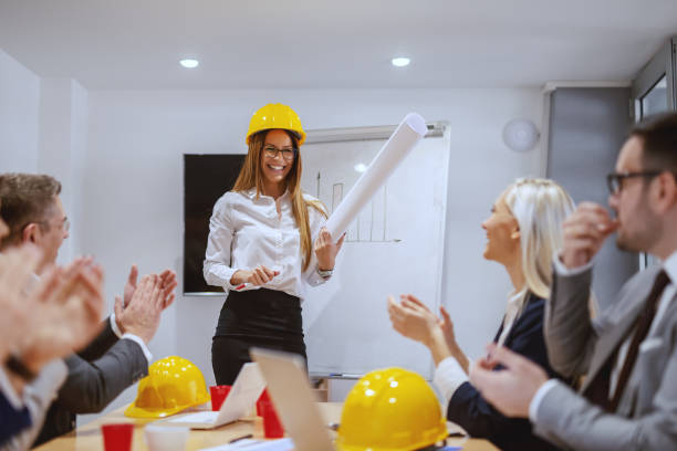 istock Smiling successful female architect standing at boardroom and talking about new project. Coworkers clapping to her. If you do what you always did, you will get what you always got. 1141975781