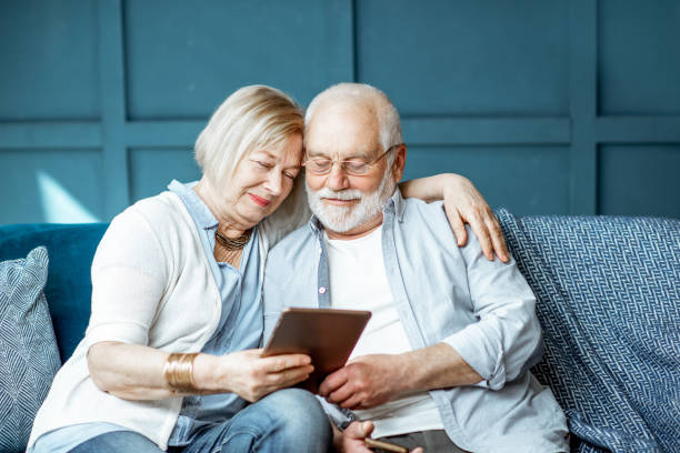 coppia senior con tablet a casa - grandparent adult smiling looking at camera foto e immagini stock