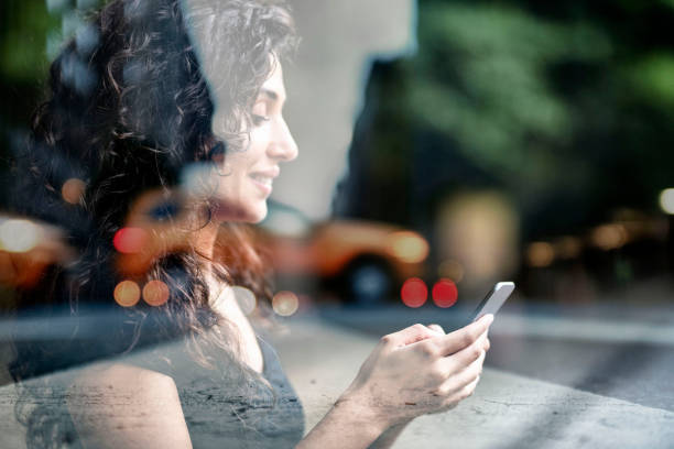 istock Woman's hand using smart phone reflection of city view, double exposure 1141985782