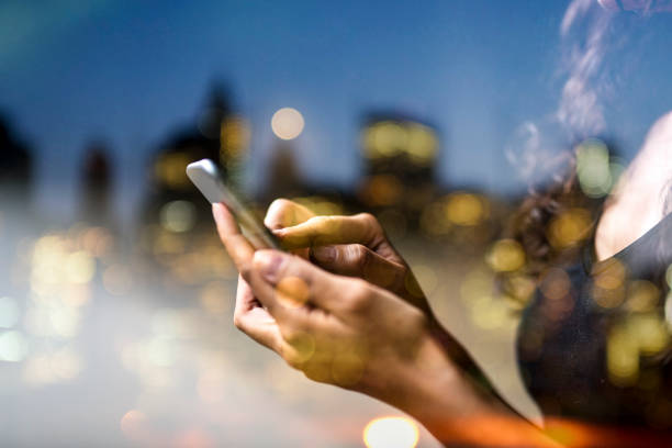 istock Woman's hand using smart phone reflection of city view, double exposure 1141987880