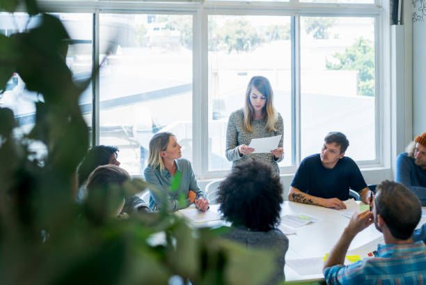 businesswoman giving presentation to colleagues - board room business conference table window imagens e fotografias de stock