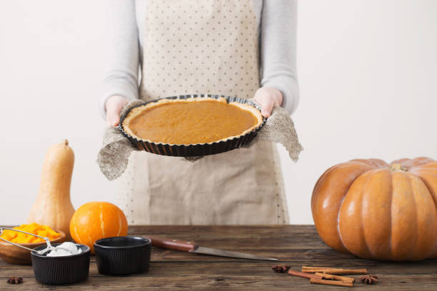 istock woman cooks pumpkin pie on white background 1141991055
