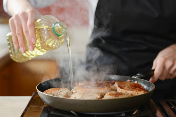 The chef in the kitchen prepares fresh pork steaks on a griddle with steam, the menu is homemade cooking culinary recipes. restaurant menu. Delicious food, recipes and cooking