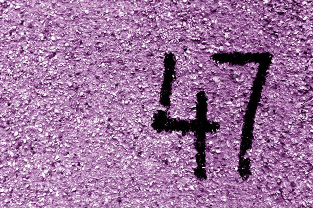istock Number 47 on cement wall in stencil in purple tone. 1141991596