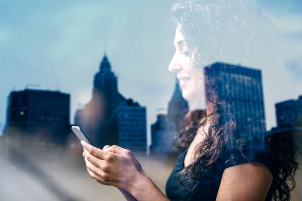istock Woman's hand using smart phone reflection of city view, double exposure 1141993190