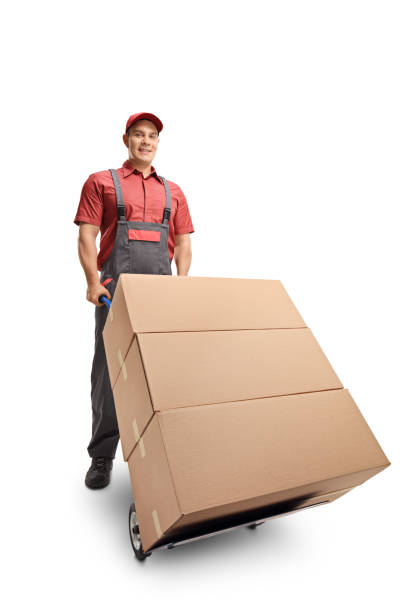 istock Male worker with a stack of boxes on a hand truck smiling at the camera 1141994618