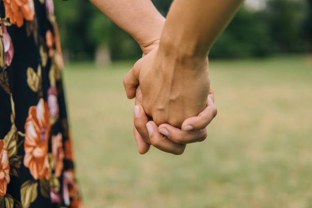 Two young female friends holding their hands outdoor in springtime Loving lesbian couple holding their hands outdoors civil partnership stock pictures, royalty-free photos & images