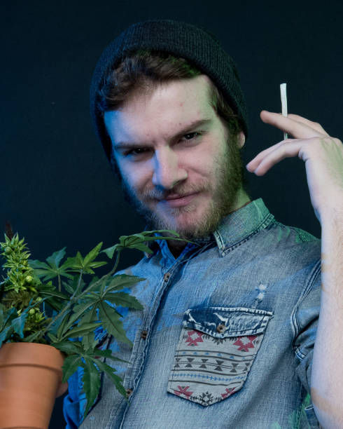 istock Young stoner man standing with marijuana plant 1141996266