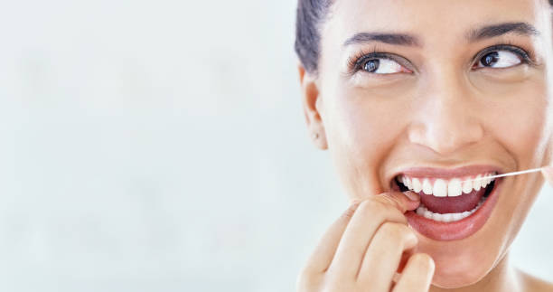 Take better care of your teeth Cropped shot of an attractive young woman flossing her teeth in the bathroom at home dental floss stock pictures, royalty-free photos & images