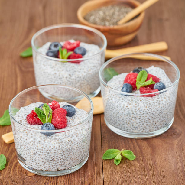 istock Chia pudding with fresh berries raspberries, blueberries. Side view, three glass on brown wooden background, close up. 1142002176