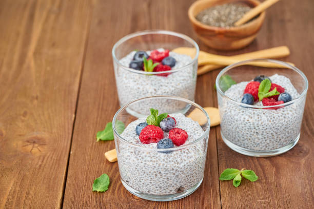 istock Chia pudding with fresh berries raspberries, blueberries. Side view, three glass on brown wooden background, copy space. 1142002323