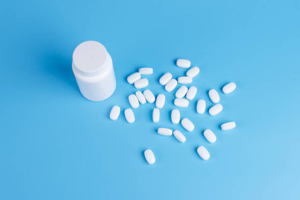 istock White pills, tablets and white bottle on blue background. Copy space for text 1142003797