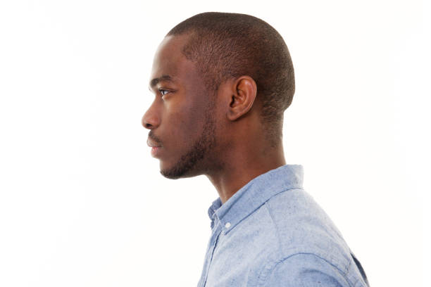 Close up profile of handsome young black man against isolated white background Close up profile portrait of handsome young black man against isolated white background staring photos stock pictures, royalty-free photos & images