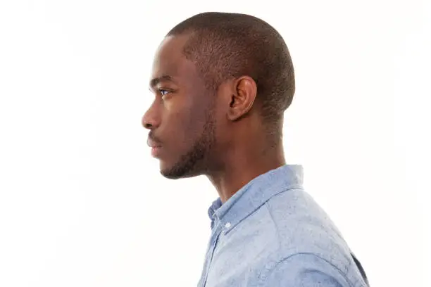 Close up profile portrait of handsome young black man against isolated white background