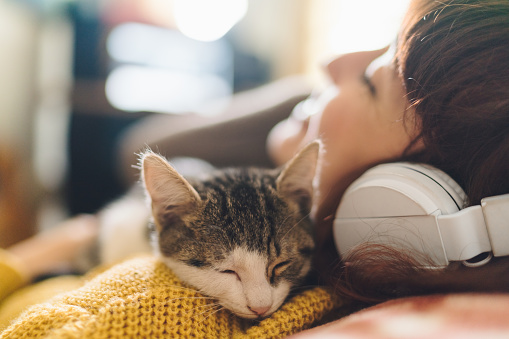 Gen Z girl with eyes closed hugging a cat and enjoying music