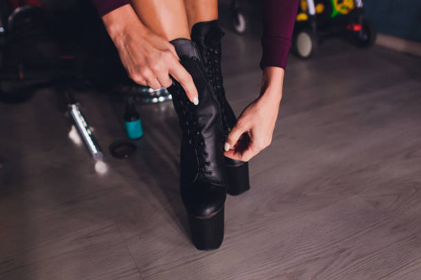 istock Woman puts on shoes and dance on pole studio. 1142010842