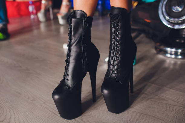 istock Woman puts on shoes and dance on pole studio. 1142010851