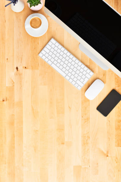 Desktop computer. Top view of wooden office desk with large desktop computer, keyboard, mouse, smartphone and cup of coffee. All in one computer. Modern workspace. Copy space.
