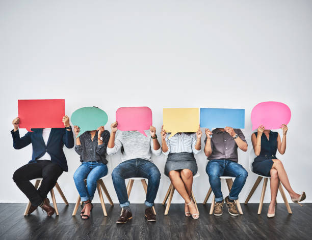 So, what do you say? Studio shot of a group of young businesspeople holding colorful speech bubbles in line against a grey background people in a row photos stock pictures, royalty-free photos & images