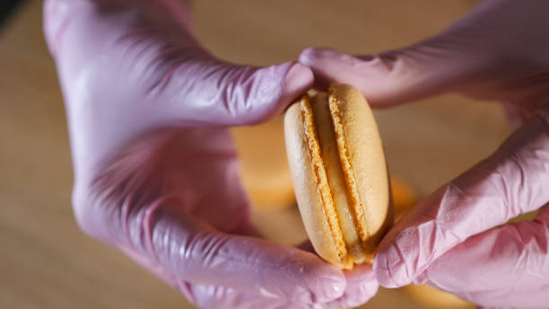 istock Pastry chef is filling lemon macaroons with cream using confectionery bag. 1142015941