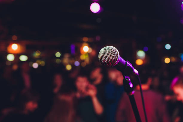 microphone avec la lumière vive colorée floue dans le fond sombre de nuit, image de mise au point douce pour les concepts de communication de technologie d’affaires. - new housing audio photos et images de collection