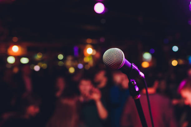 microfono con luce intensa colorata sfocata in sfondo notturno scuro, immagine soft focus per i concetti di comunicazione della tecnologia aziendale. - karaoke foto e immagini stock