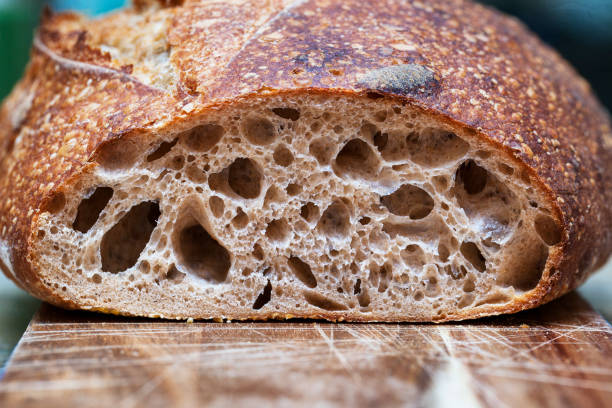 barra crujiente de pan de masa fermentada recién horneada boule. rebanadas de pan de masa fermentada en tablero de madera. comida sana. textura crujiente de pan artesanal - enzo fotografías e imágenes de stock