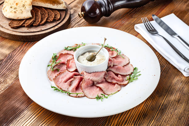 die aussicht auf die traditionelle italienische küche vitello tonnato. ein gericht mit eingelegter kalbs-thunfischcreme-sauce und brot auf holzhintergrund. kopierraum für design, text. snack vor dem mittagessen. essen in der nähe - caper sauce stock-fotos und bilder