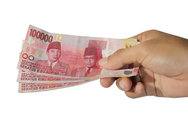 Photo of hands giving out one hundred thousand money on white background, rupiah money, hand showing 100000 rupiah money