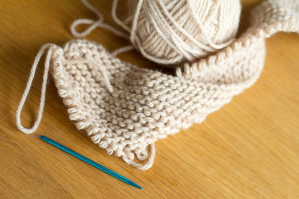 istock Extremely close-up knitting from beige yarn, needle, crochet hooks. Work on a new product. Selective soft focus. 1142028095