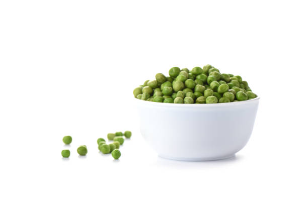 istock Green peas in a white bowl isolated on white background. Copy space 1142028525