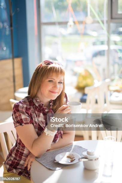 Foto de Uma Menina Com Cabelo Vermelho Sentase Em Um Café Do Verão Com Uma Chávena De Café Europeu Com Pele Justa e mais fotos de stock de Adolescente